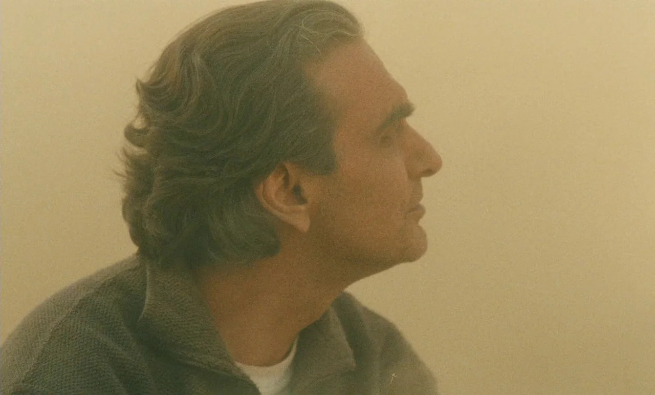 Taste of Cherry (1997) movie still: closeup — An interior space is filled with a uniform yellowish haze or light. A man with dark hair looks toward…