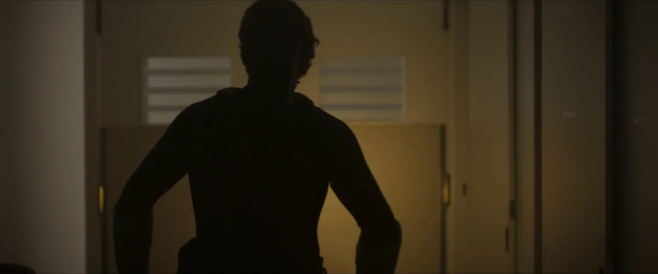 Apocalypse Z: The Beginning of the End (2024) movie still: medium — A dimly lit indoor passage features a single doorway emitting soft golden light.…