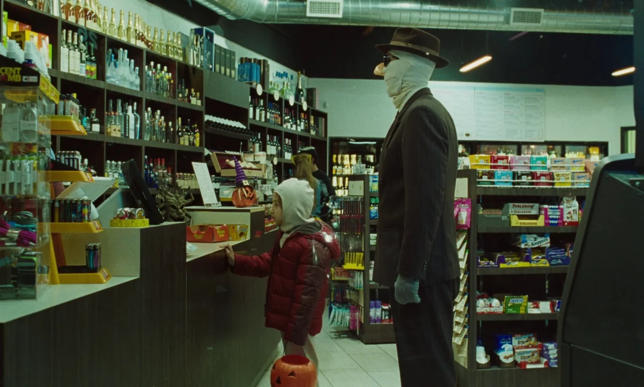 Marriage Story movie still: medium — A brightly lit convenience store aisle features shelves stocked with various liquor and candy. An adult with a…