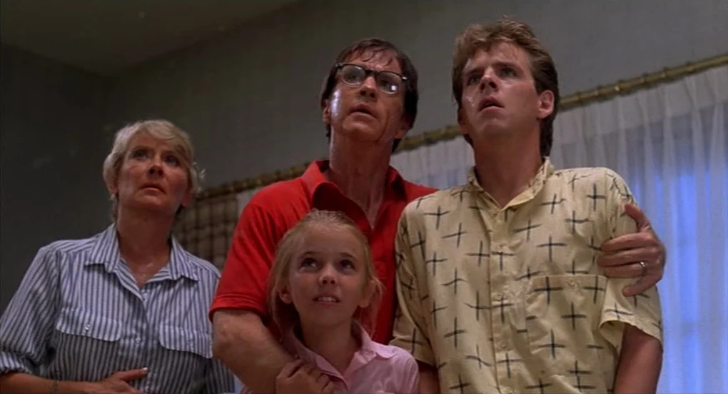 A Nightmare On Elm Street 2: Freddy’s Revenge (1985) movie still: medium — A family stands in a residential room with white curtains visible in the…