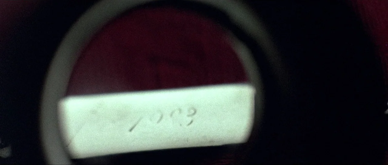 Opera (1987) movie still: closeup — A close up view of a motion picture projector gate containing film leader. A white rectangular frame displays…