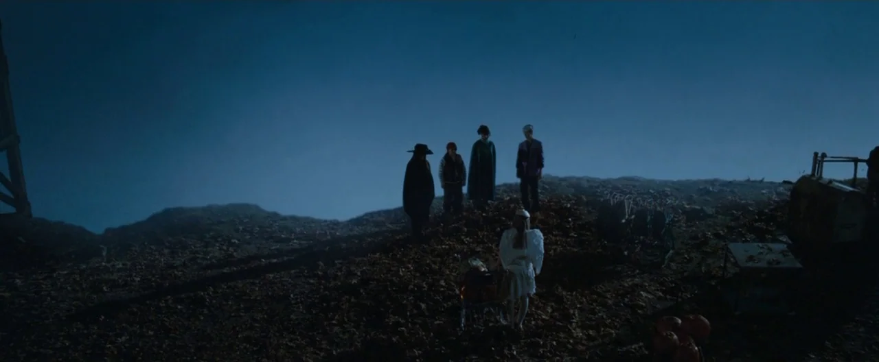 Trick ‘R Treat (2007) movie still: wide — A group of children in costumes stand on a dark, desolate hill at night. The landscape is sparse and…