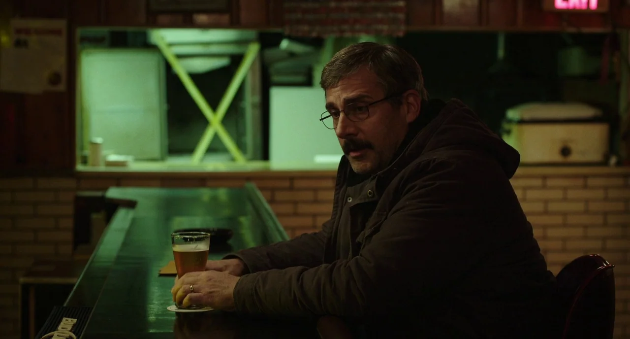 Last Flag Flying (2017) movie still: medium — A dimly lit bar with brick walls and a dark wooden counter surface. A man with a mustache sits alone…