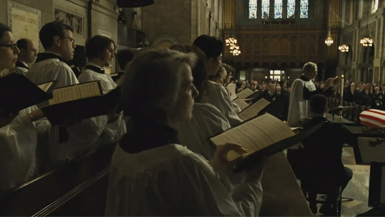 Salt (2010) movie still: medium — A church choir stands in rows during a service, illuminated by internal chandeliers. Multiple choir members in…
