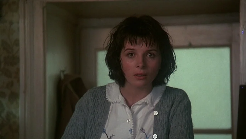The Unbearable Lightness of Being (1988) movie still: medium — A woman stands in a bright room against a window with a translucent pane. She faces…