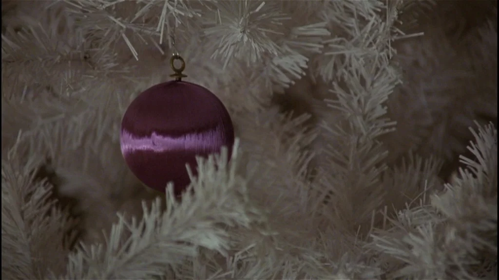 Goodfellas (1990) movie still: closeup — A close-up view of a purple satin ornament hanging from white pine needles. The ornament is the focal point…