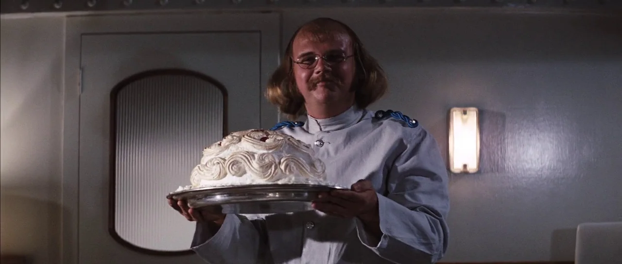 Diamonds Are Forever (1971) movie still: medium — An interior ship cabin with smooth walls and a wall-mounted rectangular light fixture. A man in a…