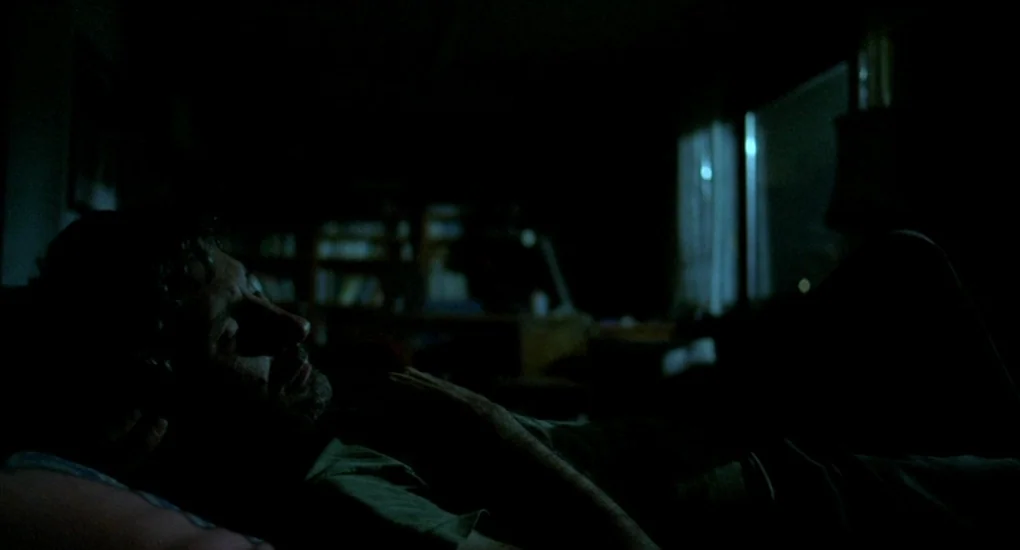 Uzak (2002) movie still: medium — A dark, dimly lit bedroom at night with a single window as a source. A man lies horizontally in bed facing away…