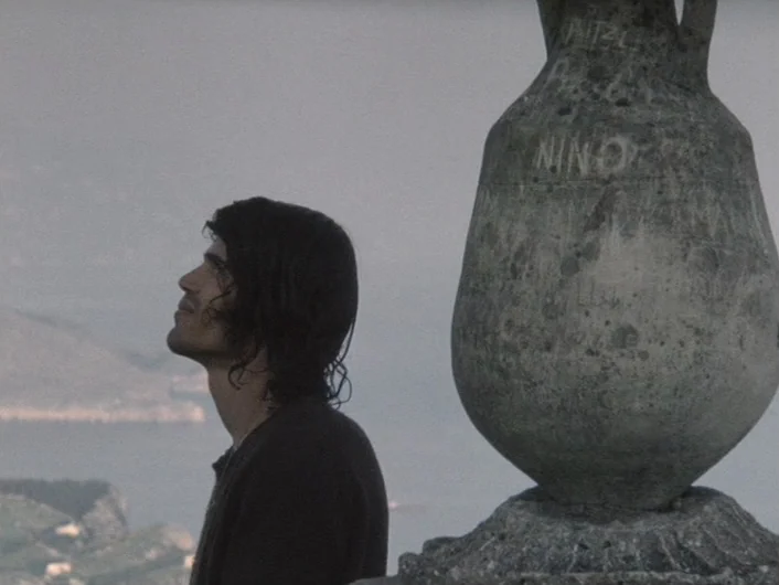 Eika Katappa (1969) movie still: medium — An outdoor overlook features a weathered stone urn engraved with text in the foreground. A young man…