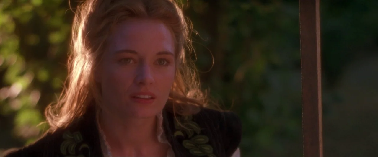 Dangerous Beauty (1998) movie still: closeup — A woman stands outdoors in the late afternoon sun against a blurred natural backdrop. She is looking…