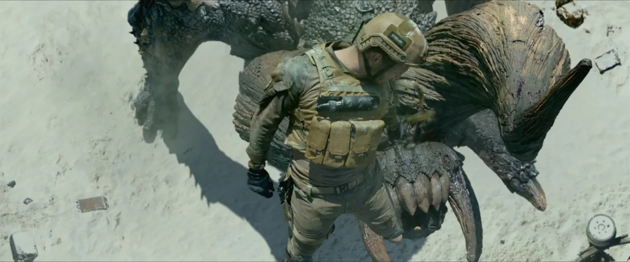Monster Hunter (2020) movie still: medium — A desolate sandy landscape features a large scaled creature coiled on the white ground. A soldier in…