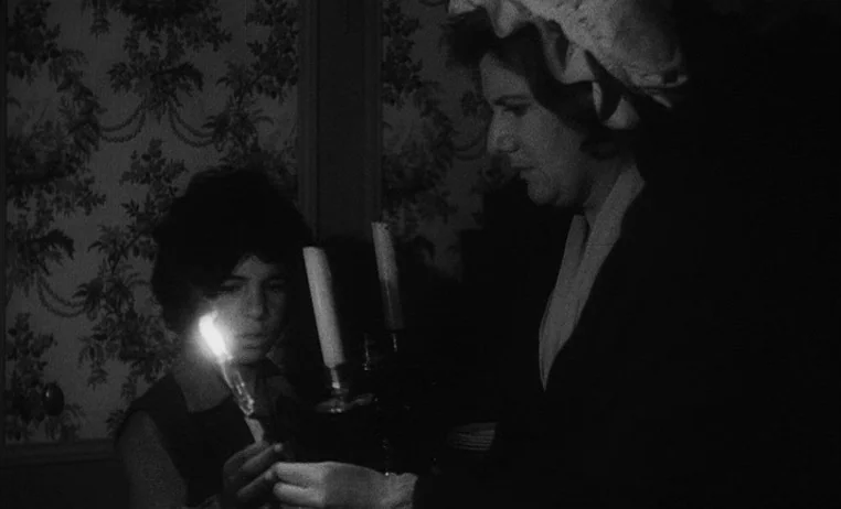 The Wild Child (1970) movie still: medium — A room with patterned wallpaper features two people holding a lit candelabra in darkness. The woman and…