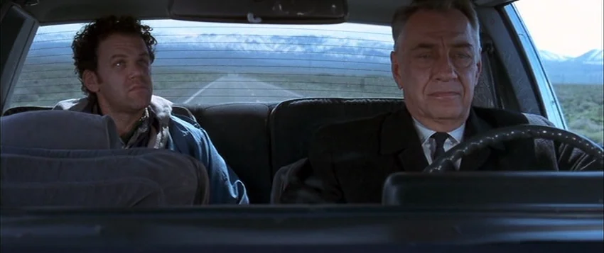 Hard Eight (1996) movie still: medium — Two men travel along a desolate road visible through the back and front windows. The older man drives the…