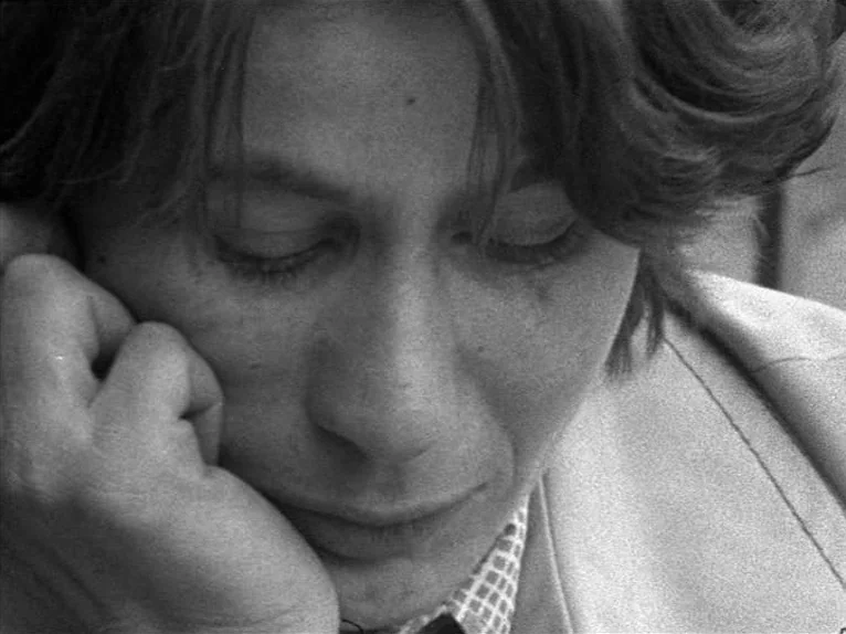 Family Nest (1979) movie still: closeup — A close portrait shows a person with their head supported by a hand. The subject has dark hair and wears a…