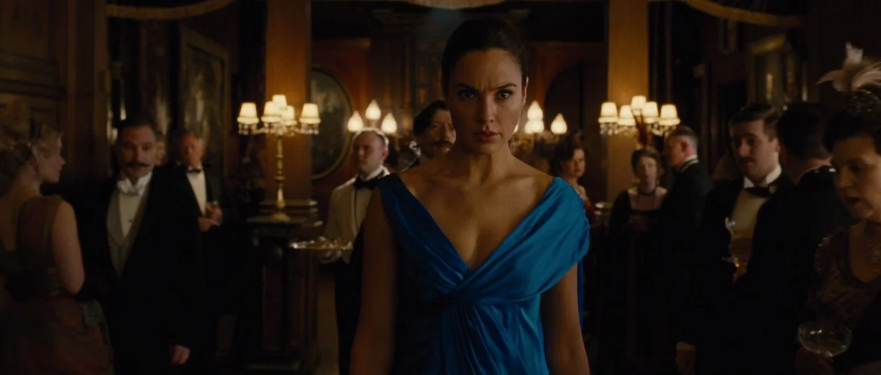 Wonder Woman (2017) movie still: medium — An opulent 1940s indoor social event featuring guests in formal wear and candelabras. A woman in a blue…