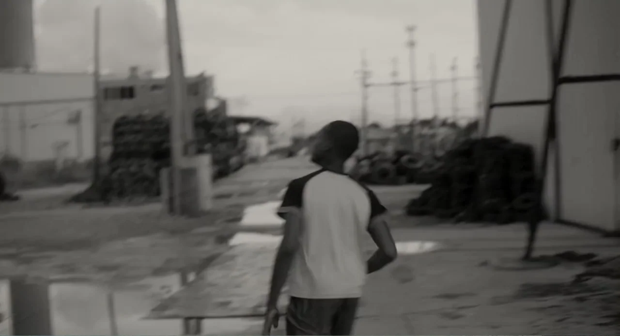 What You Gonna Do When the World's on Fire? (2019) movie still: medium — An outdoor industrial lot with scattered debris and puddles under an…