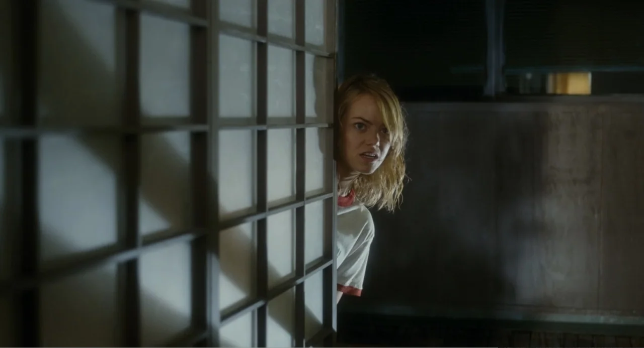 Aloha (2015) movie still: medium — An interior space features a wooden shoji-style screen partially obscuring a dim hallway. A young woman peeks…