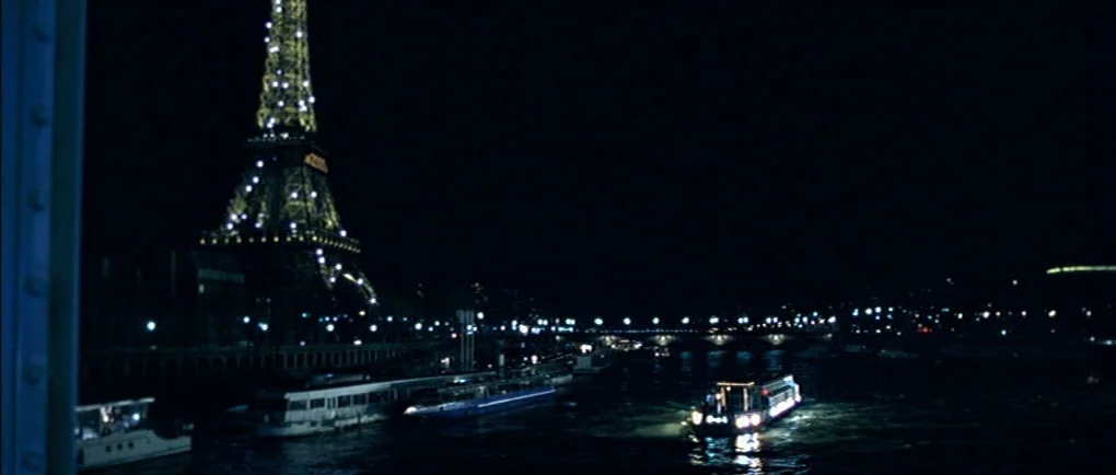 Mortal Transfer (2001) movie still: establishing — A night view of the river Seine in Paris with the illuminated Eiffel Tower. A tour boat moves…