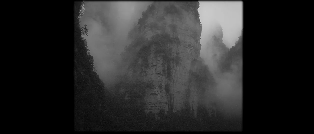 Paddington (2014) movie still: establishing — Vertical limestone karst rock formations rise through a thick layer of mountain fog. Greenery clings…