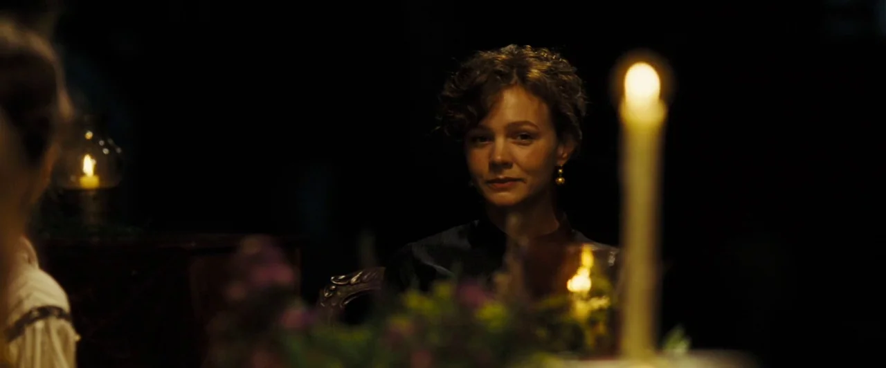 Far from the Madding Crowd (2015) movie still: medium — A dimly lit room with a dark background and a table set for dinner. A woman sits in the…