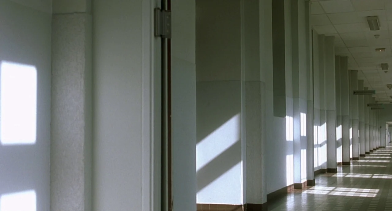 The Diving Bell and the Butterfly (2007) movie still: establishing — A long, clinical hospital hallway features white walls with recurring…