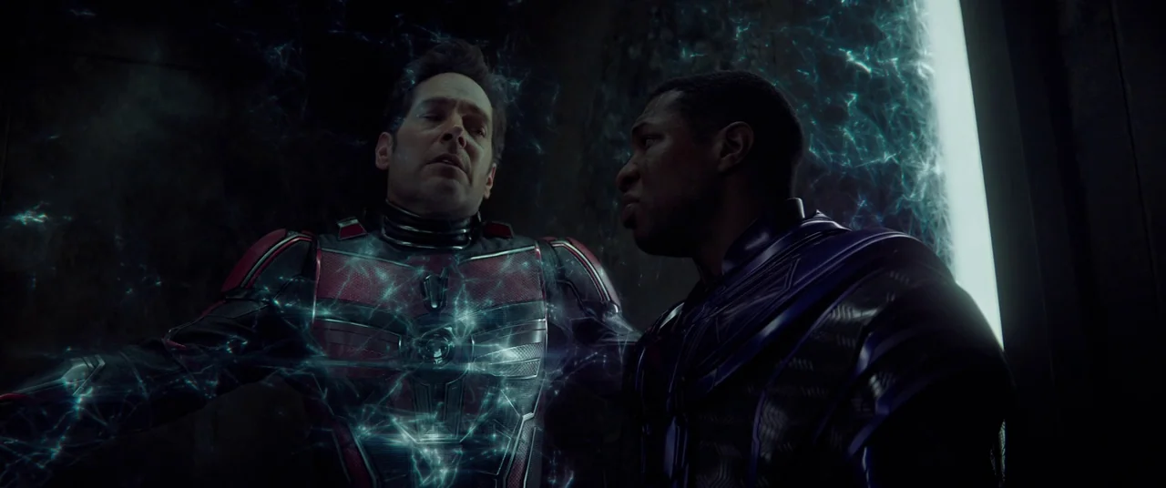 Ant-Man and the Wasp: Quantumania (2023) movie still: medium — A dark, dimly lit environment surrounded by blue crackling energy lines. Two men in…