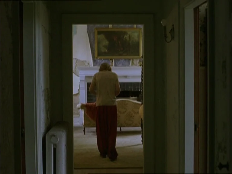 Last Days (2005) movie still: medium — A view through a narrow hallway into a room with peeling wallpaper and a fireplace. A man stands in the…