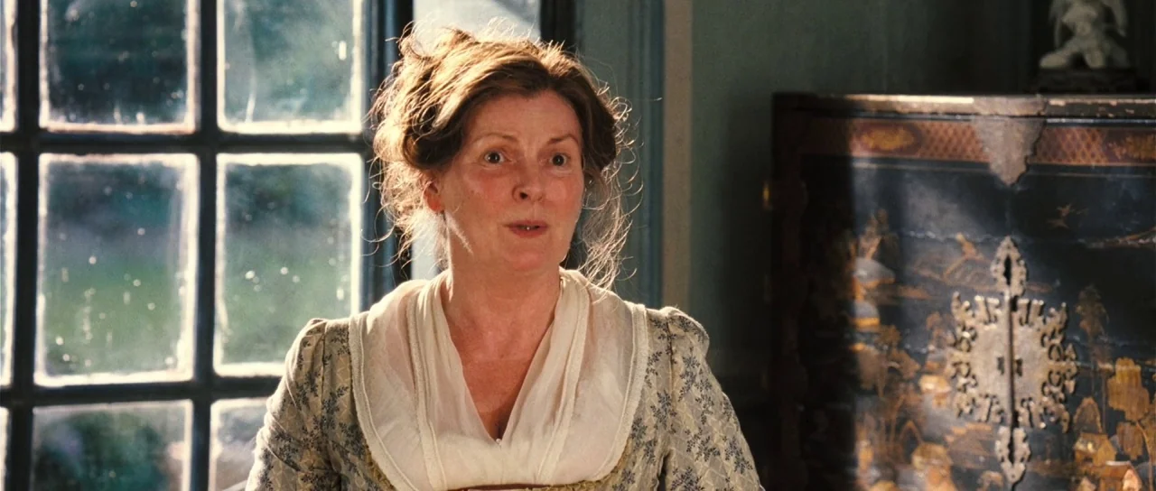 Pride & Prejudice (2005) movie still: medium — An elegant 19th-century interior features a dark lacquered cabinet and a grid-paned window. A woman…