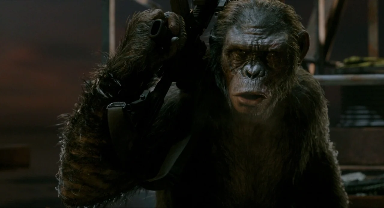 Dawn of the Planet of the Apes (2014) movie still: closeup — A dark, dimly lit outdoor setting with industrial elements partially obscured by…