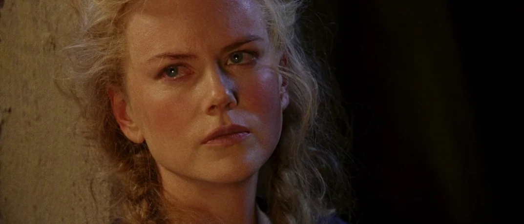 Cold Mountain (2003) movie still: closeup — A woman leans against a rough textured stone wall in a dark environment. The woman has pale skin and…