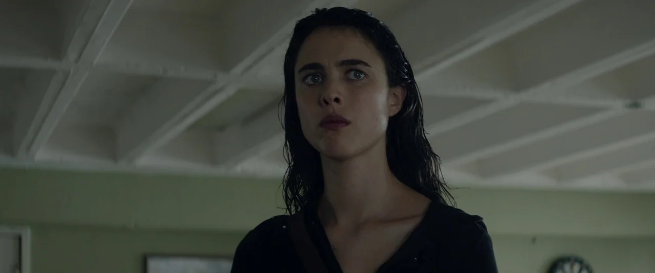 Stars At Noon (2022) movie still: closeup — A sparse, dimly lit space features pale green walls and a paneled ceiling. A woman with wet, dark hair…