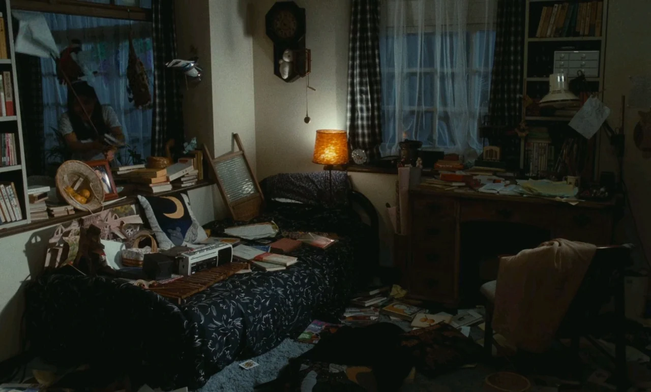 Chizuko’s Younger Sister (1991) movie still: wide — A cluttered bedroom is filled with books, papers, and various personal items scattered about.…