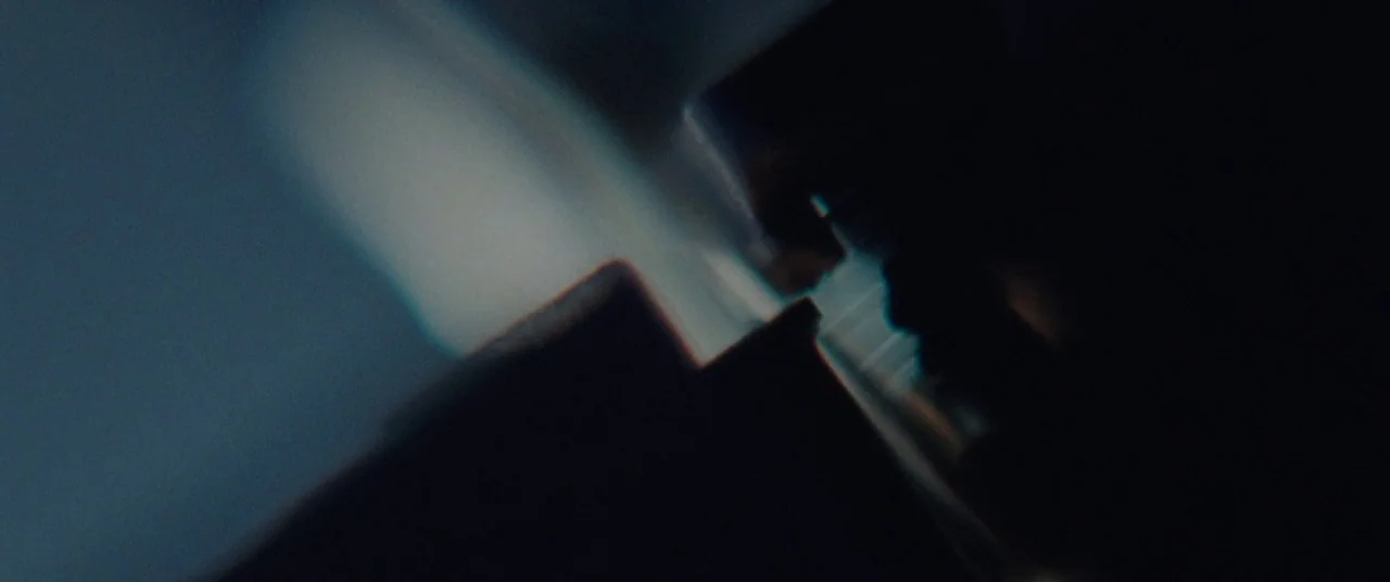 The Old Man & The Gun (2018) movie still: closeup — Dark geometric silhouettes occupy the frame against a blurred, deep blue background. The objects…