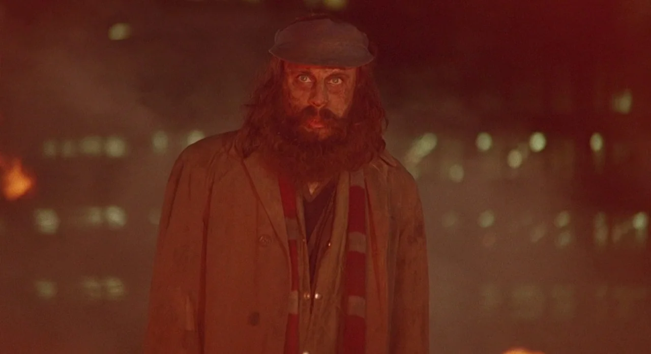 Hellraiser (1987) movie still: medium — A dark city street at night is illuminated by an intense fire source. A man with a disheveled beard stands…