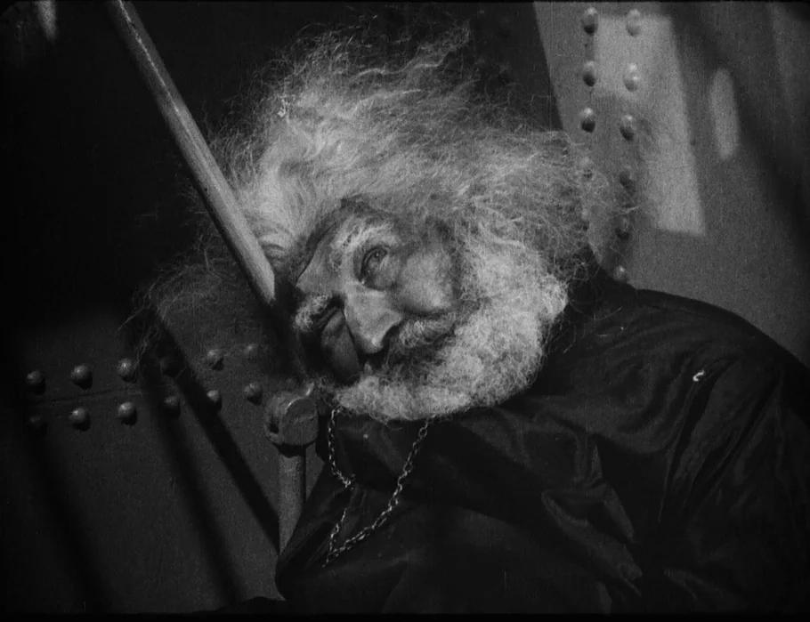 Battleship Potemkin (1925) movie still: closeup — An interior metal bulkhead of a ship features large rivets along a vertical seam. An elderly man…