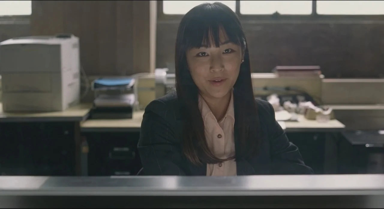 St. Vincent (2014) movie still: medium — A workspace with a large printer and desk equipment sits behind a person. The woman sits at her station…