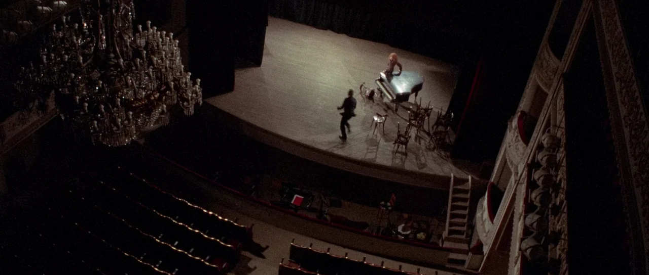 The Case of the Scorpion’s Tail (1971) movie still: wide — An empty theater auditorium features a large crystal chandelier hanging over dark velvet…