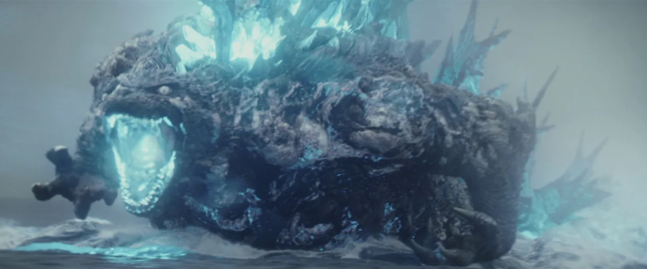 Godzilla Minus One (2023) movie still: medium — A massive reptilian monster emerges from cold, foggy waters with jagged, glowing dorsal plates. The…