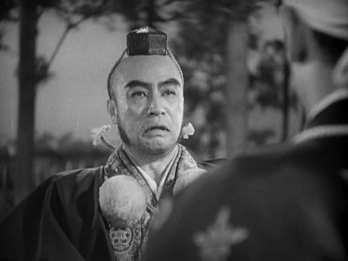 The Men Who Tread on the Tigers Tail (1945) movie still: medium — An outdoor setting with blurred trees visible behind a man in historical costume.…