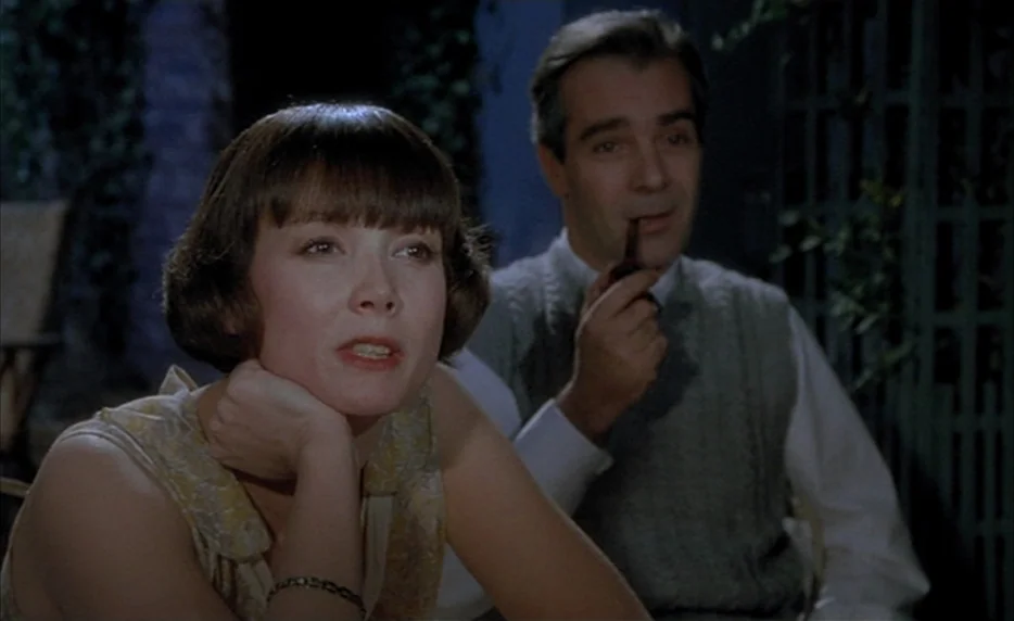 Mélo (1986) movie still: medium — A nighttime outdoor setting with climbing ivy visible on a green metal trellis frame. A woman and a man sit…