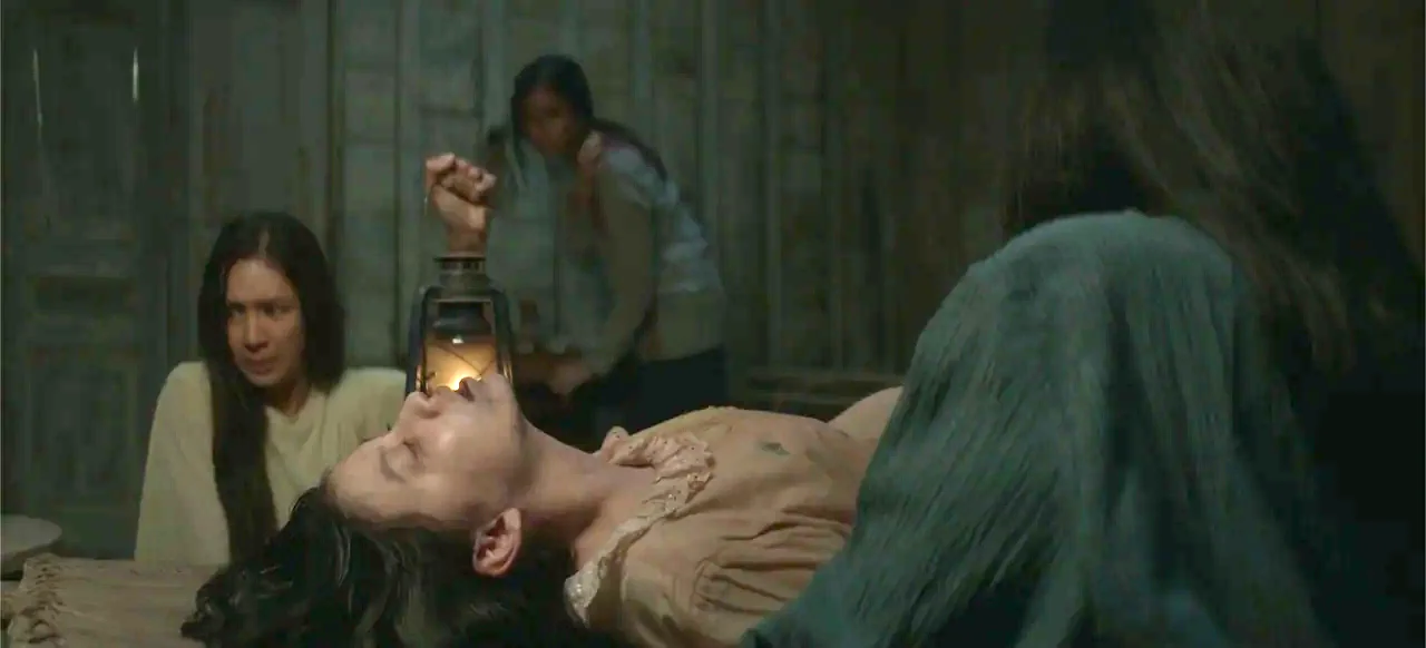 A Thousand Days (2023) movie still: medium — A dim, cramped wooden interior features rough-hewn planks and sparse, antique furnishings. A young…