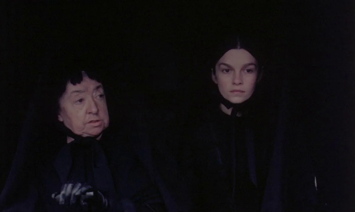 Kamouraska (1973) movie still: medium — Two women in dark mourning attire sit in a shadowed, enclosed space. They appear to be in a carriage or…