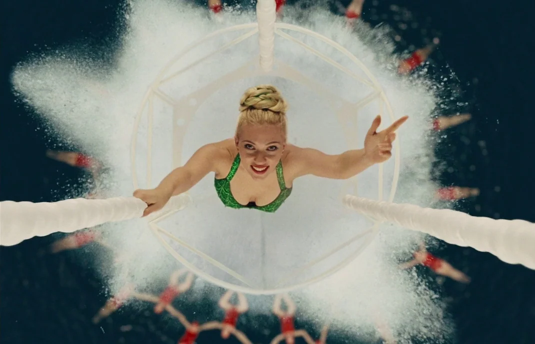 Hail, Caesar! (2016) movie still: medium — A woman in a green leotard rises through a circular white frame above water. Below her a group of…
