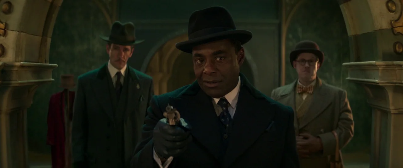 Wonka (2023) movie still: medium — An opulent interior space with arched doorways and dark stone walls suggests a mansion. Three men in 1940s-style…