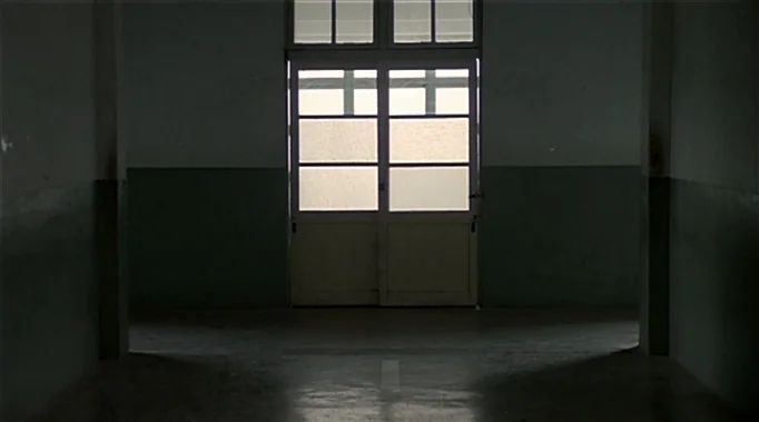 A Time To Love and A Time To Die (1985) movie still: establishing — A stark corridor features paneled walls painted with a dark lower-wall trim. A…
