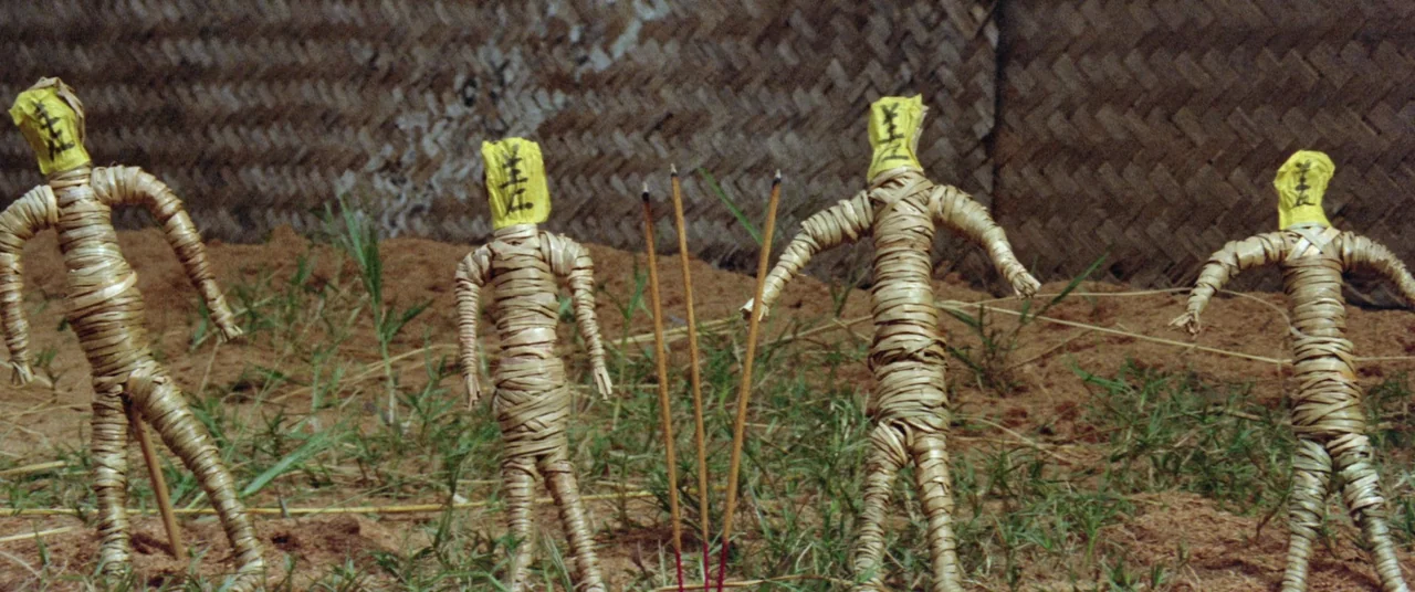 Encounter of the Spooky Kind (1980) movie still: medium — Four woven straw effigies with yellow paper heads stand in a patch of dirt. Three incense…