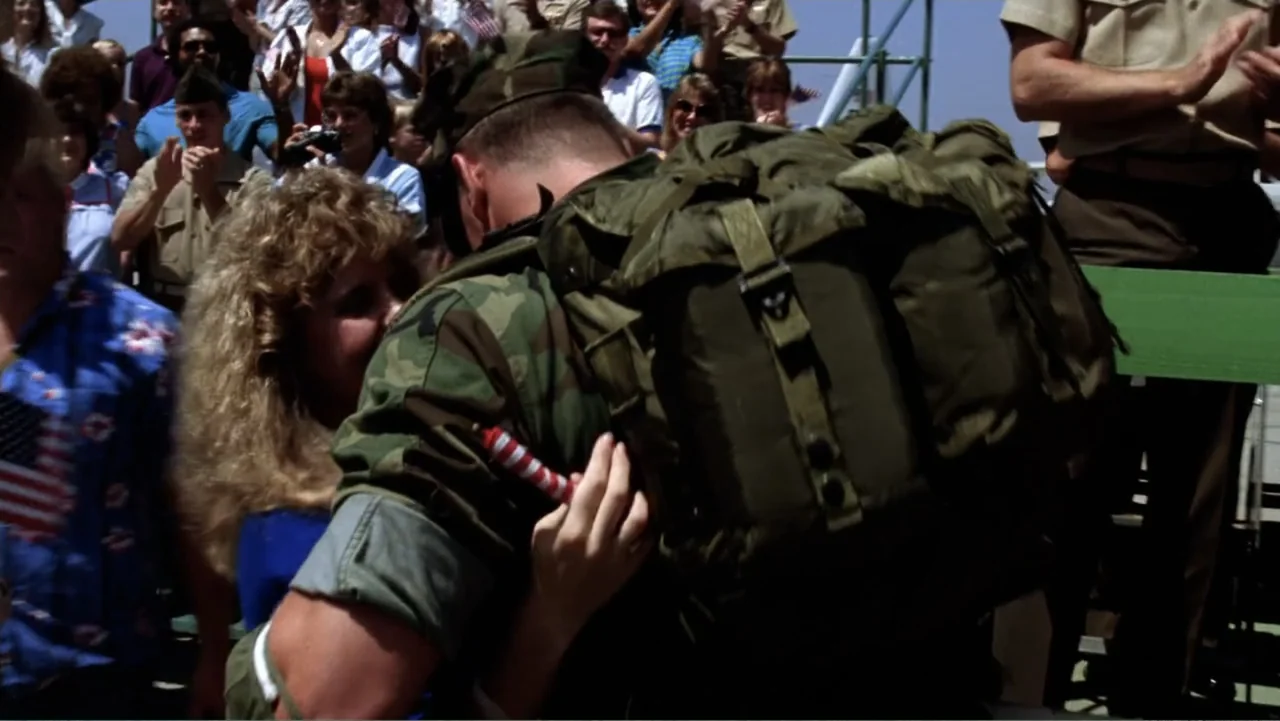 Heartbreak Ridge (1986) movie still: medium — A sunlit outdoor crowd gathers to watch military personnel during a ceremonial public event. A soldier…