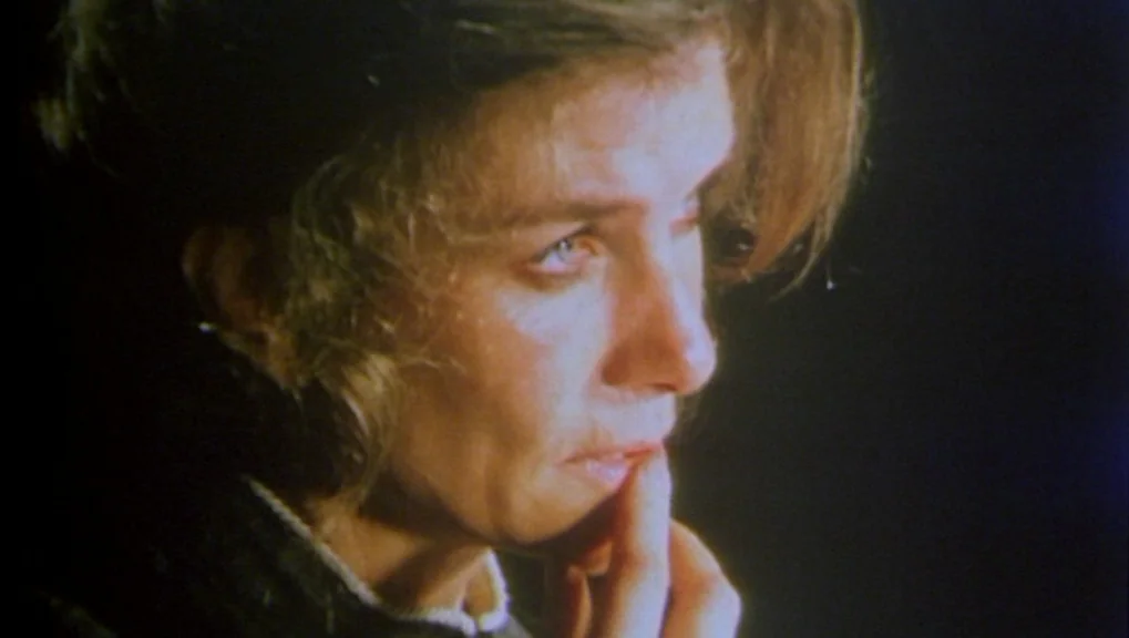 War Requiem (1989) movie still: closeup — A dimly lit room provides a dark background for the close-up shot. A woman touches her lip while looking…