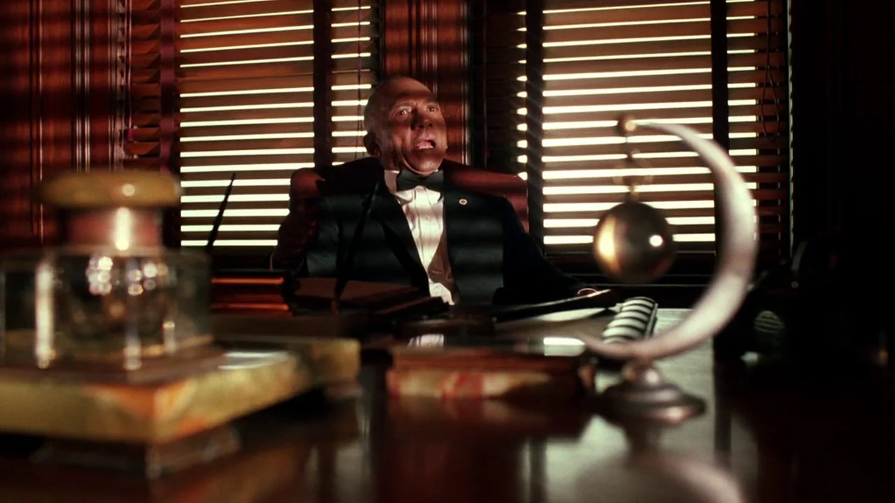Malcolm X (1992) movie still: medium — A mahogany-paneled room features a heavy desk cluttered with vintage stationery and metal ornaments. A man…