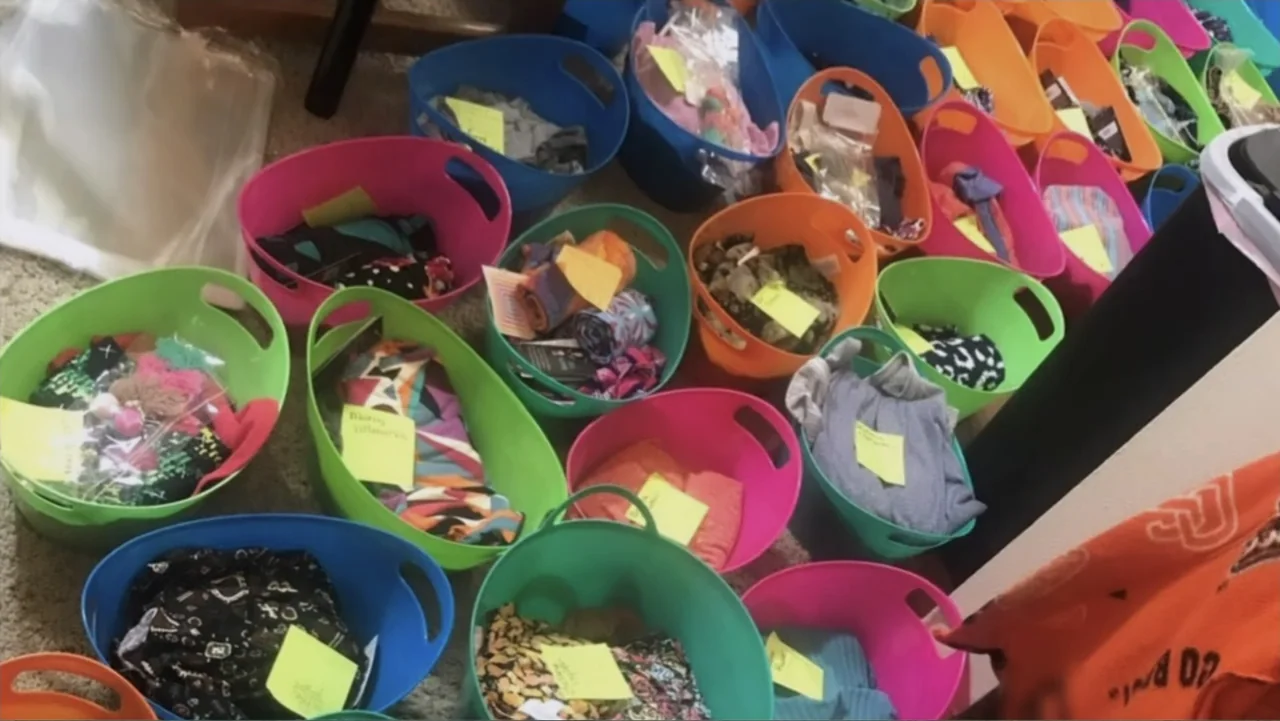 The Rise and Fall of Lularoe (2021) movie still: wide — A collection of colorful plastic bins are arranged across a carpeted interior floor. Each…